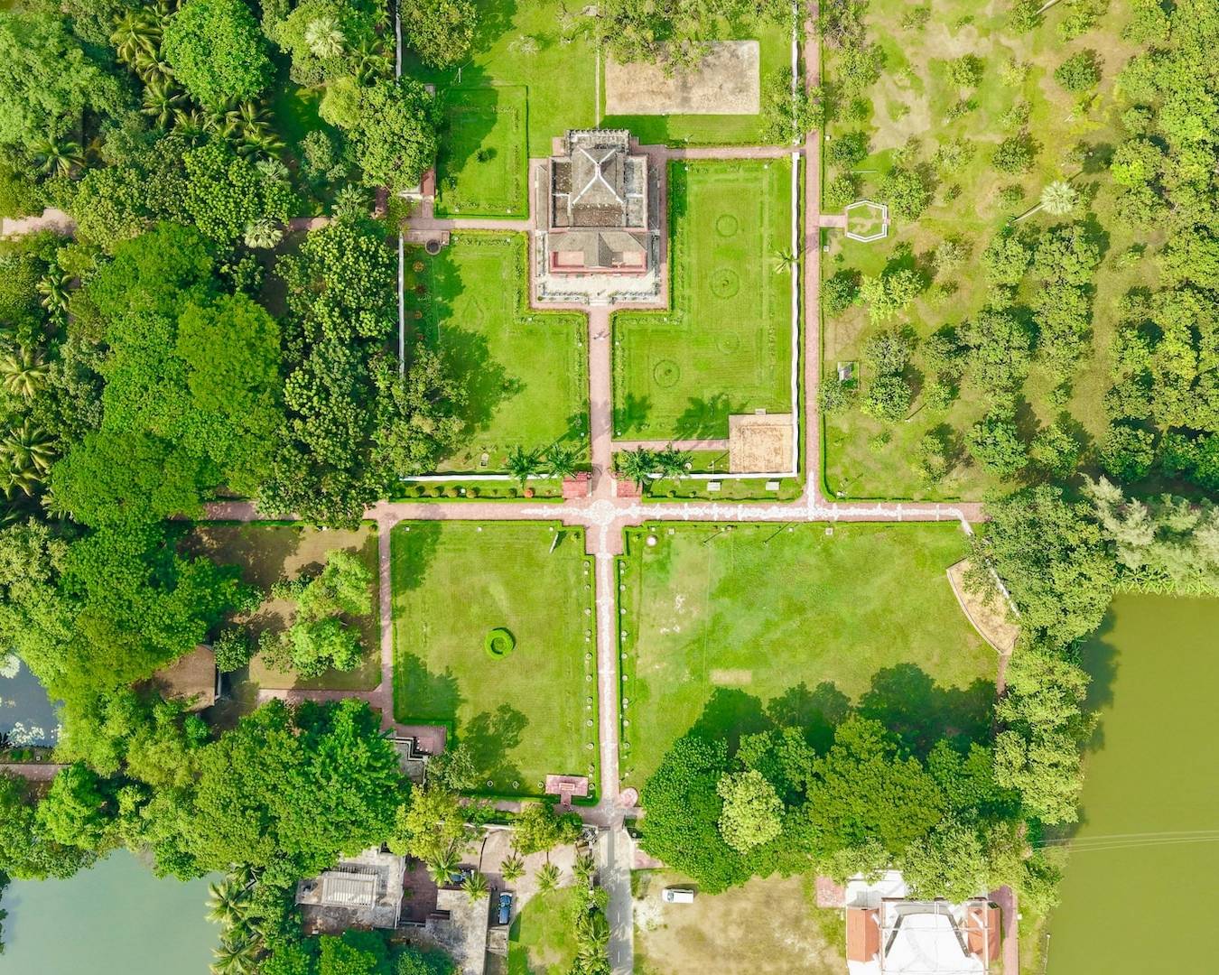 Vue aérienne d'une grande mansion avec jardins formels, pelouses, allées et plans d'eau, illustrant le concept d'être riche en biens mais pauvre en liquidités en gestion de patrimoine