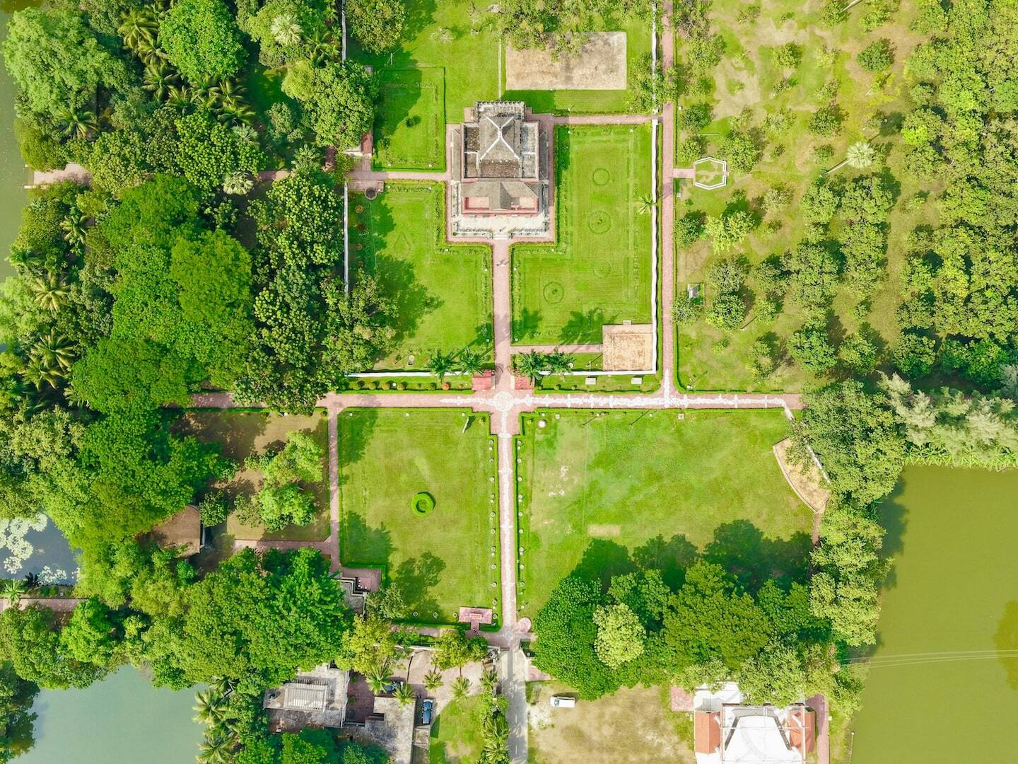 Vista aérea de una gran mansión con jardines formales, céspedes, senderos y cuerpos de agua, ilustrando el concepto de ser rico en bienes pero pobre en liquidez en gestión de patrimonio