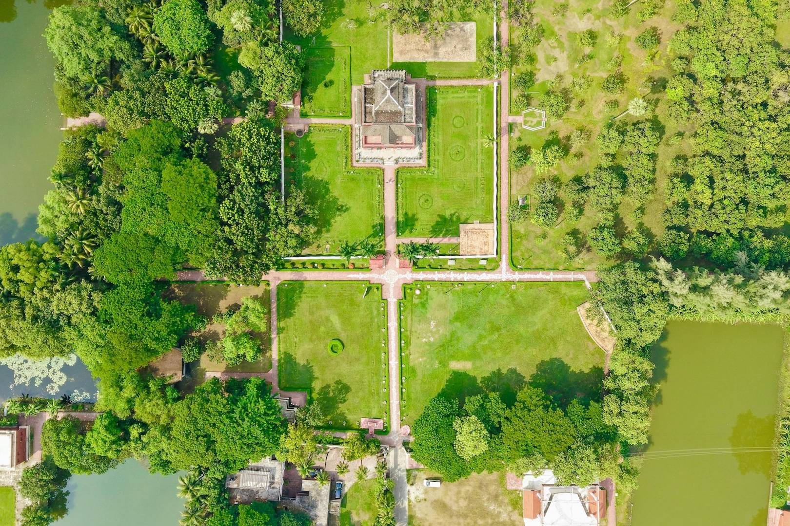 Vue aérienne d'une grande mansion avec jardins formels, pelouses, allées et plans d'eau, illustrant le concept d'être riche en biens mais pauvre en liquidités en gestion de patrimoine